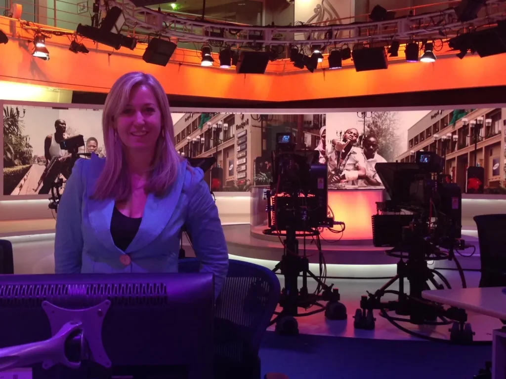 Erica Wood behind the scenes in the Al Jazeera broadcast studio in Qatar, surrounded by cameras and newsroom lights.