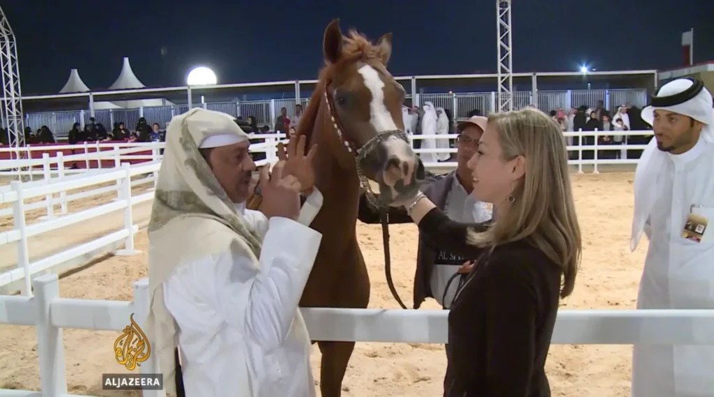 Erica Wood reporting from a horse show in Qatar for Al Jazeera, interviewing participants during the event.