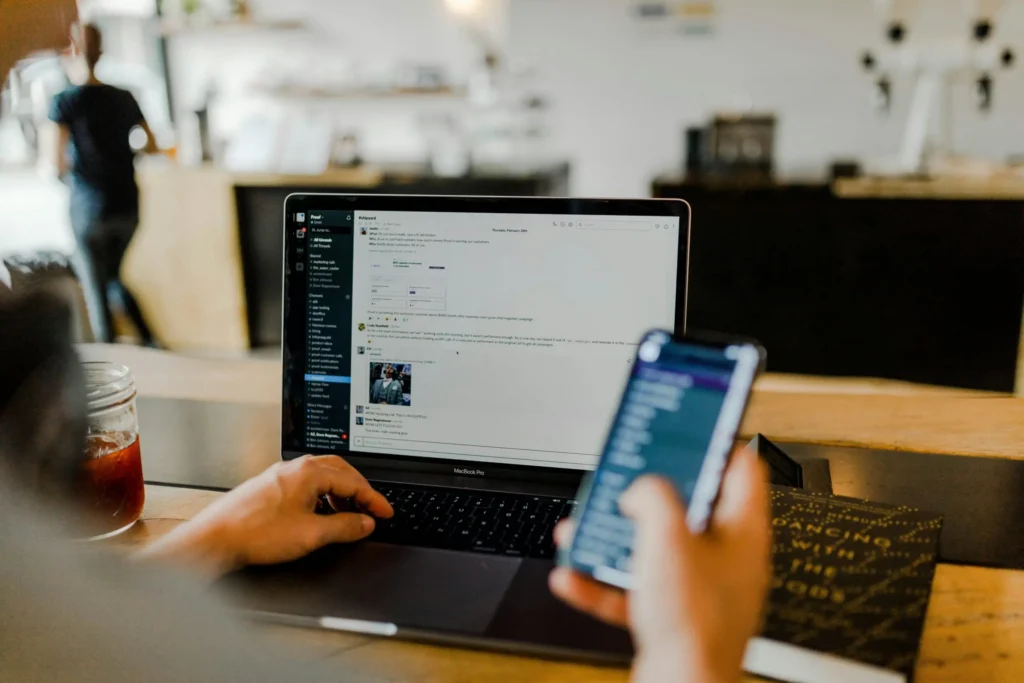 Person working on a laptop and phone, coordinating a media campaign and communications strategy.