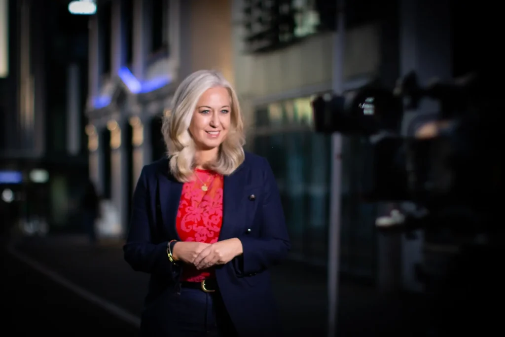 Media consultant Erica Wood standing outside a newsroom, ready to help professionals elevate their media skills and communicate with confidence.